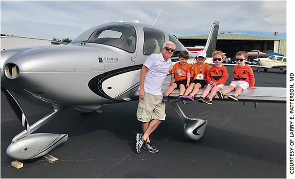 Larry E. Patterson, MD, poses with his grandchildren, seated on the wing of his personal plane. From left to right, the grandchildren are Finn, Rosie, Chase and Ethan.