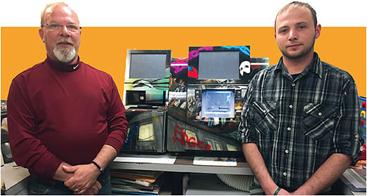 Alan Bardfield, left, and his son Stephen in Thames Optical’s in-house finishing lab. The edger sports a custom silk screen of a gritty NYC streetscape that was part of a Vision Expo East in-booth promotion a few years ago.