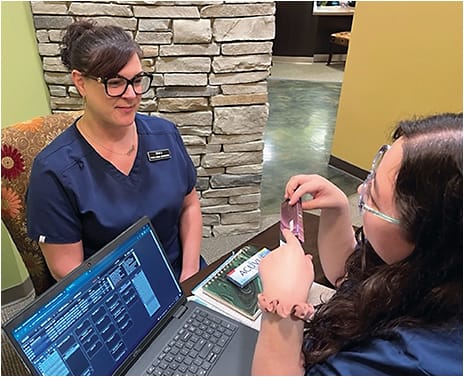 A tech in Dr. Earley’s clinic discusses multifocals for presbyopia with another staff member.Photo courtesy of Dr. Timothy Earley.