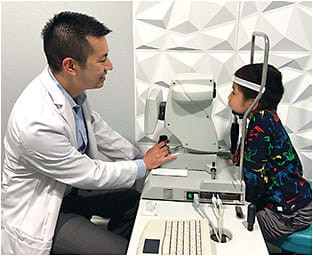 Figure 1. Dr. Mai performing an eye examination for his son Jackson.