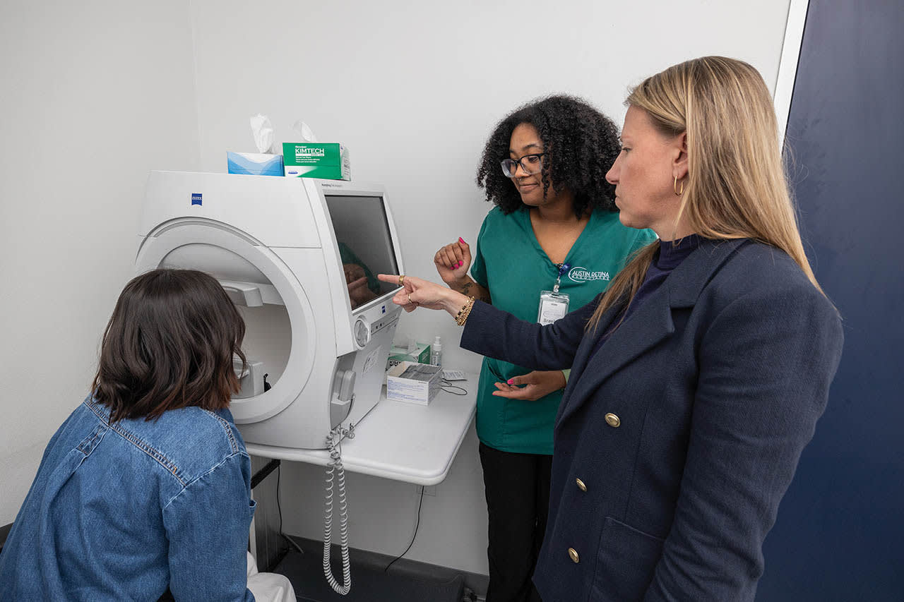Stephanie Collins, CEO (right), assisting with teaching a new clinic team member, Braelyn Mouton (middle) about performing visual fields on a Zeiss Humphrey Field Analyzer 3.