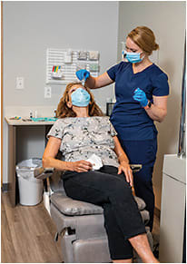 Angela Hickle, a lead technician, instills eye drops post injection.