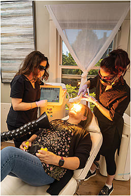 Laura M. Periman, MD (left), observes Raquel McJunkin, master aesthetician and study coordinator, as she performs an IPL procedure (OptiLight, Lumenis).