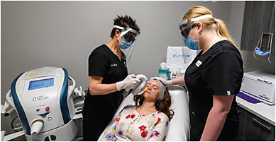 Dr. Watson performs an IPL treatment, with assistance from Ms. Sorlin-Davis (right). To address the pandemic, the practice has implemented additional safety protocols for the treatment. For example, because the patient does not wear a mask during the five- to 10-minute procedure, as it would interfere with the treatment area, the patient is asked not to speak or open their mouth. In addition, Dr. Watson and the staff wear both face shields and masks during the procedure.