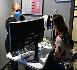 Ms. Sorlin-Davis (left) takes OCULUS Keratograph 5M images of the tear film, eyelid margins, and cornea of the patient.