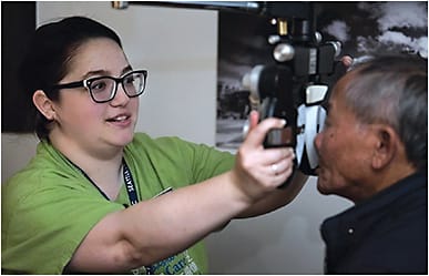 Lynn Girdlestone, COA, OSA, OSC, gives a refractive exam to a patient at the Seattle/King County Clinic, part of VOSH International, where she serves as a vision director. COURTESY OF AUSTON JAMES