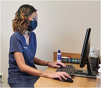 Amy M. Combs, OD (▲ top), performs a slit lamp evaluation as Sophia Nguyen, ophthalmic technician assistant (▲ above), scribes.