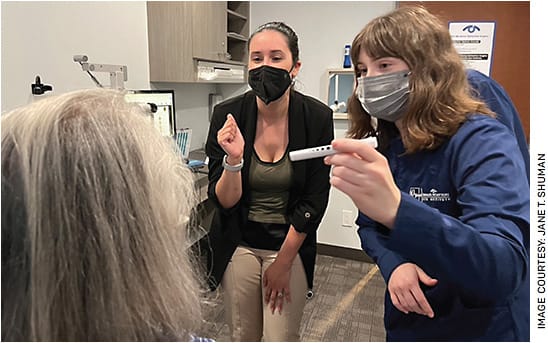 Brenea Facchini, COMT (center), instructing a new tech on penlight techniques.