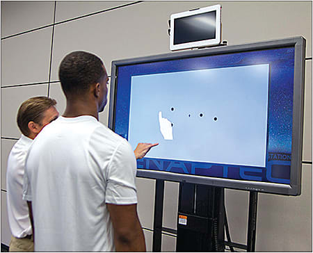 A demonstration prepares an athlete for multiple object tracking on Senaptec Sensory Station.
Courtesy of Jayson Teig/High Performance Vision Associates