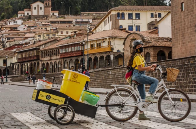 A photograph of a woman hauling buckets of compost with a bicycle in Cusco’s Plaza de Armas.