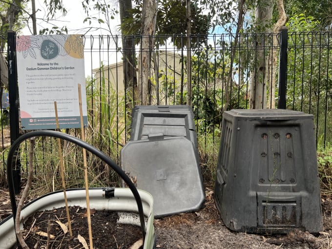 A photograph of a black compost bin inside a park.