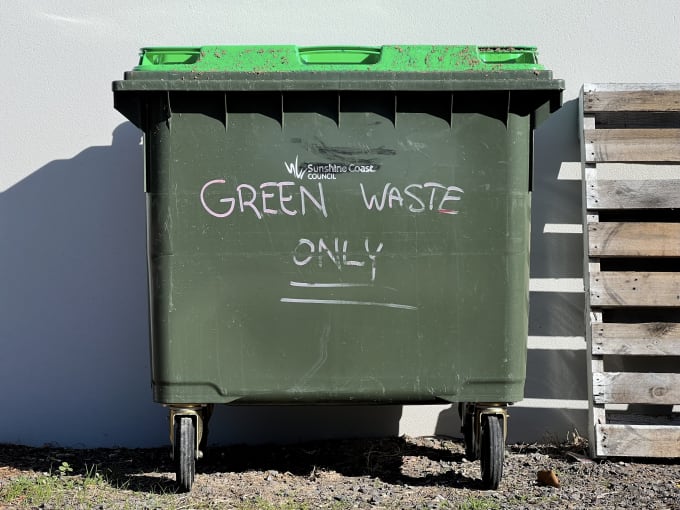 A photograph of a large green bin with ‘Green Waste Only’ written on it.