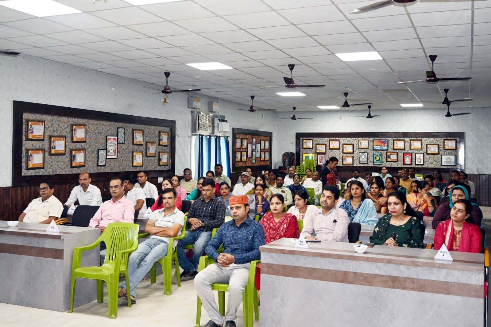 Parents of Sunbeam School Ballia seated at desks carrying class nameplates during a Parents' Forum session.
