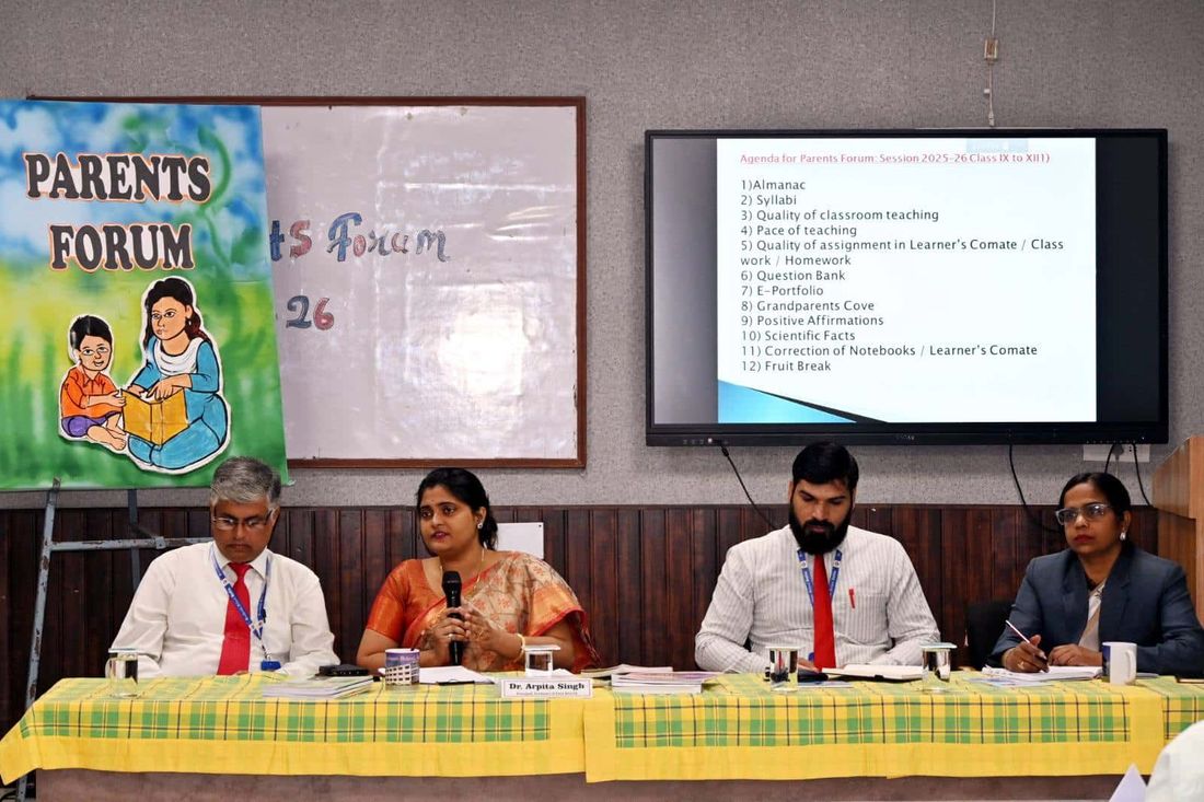 The Parents' Forum agenda projected on a screen at Sunbeam School Ballia, with a panel of the school's leadership seated beneath it behind a name plate