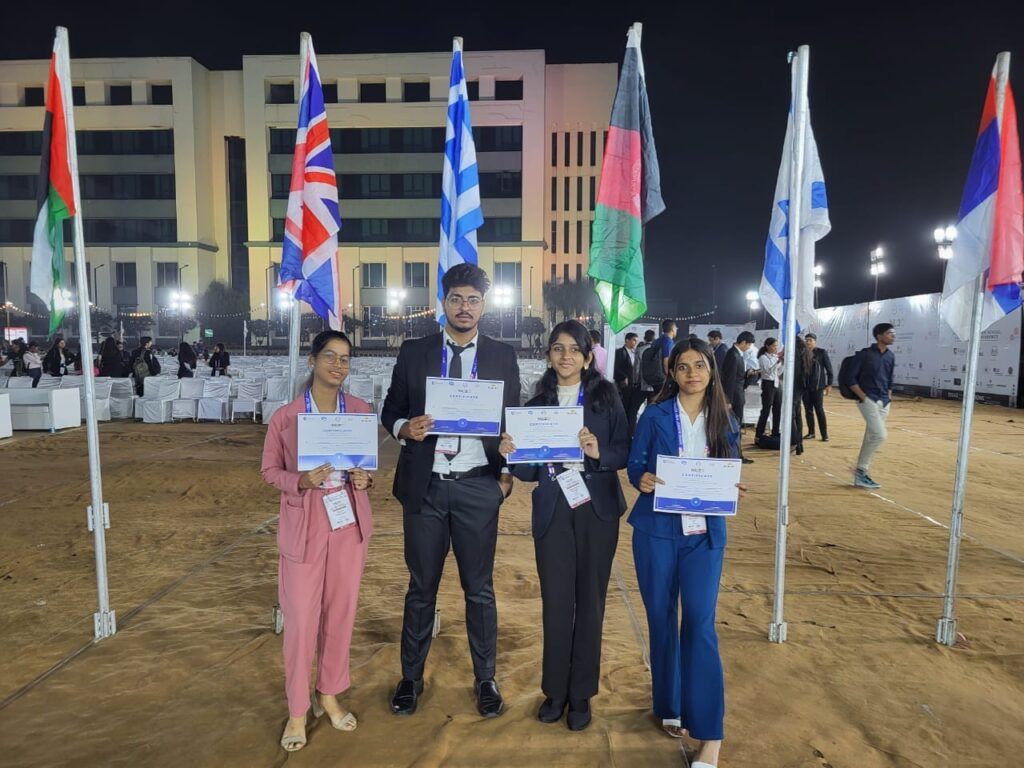 Delegates from Sunbeam School Ballia holding their Model United Nations certificates in front of the national flags.