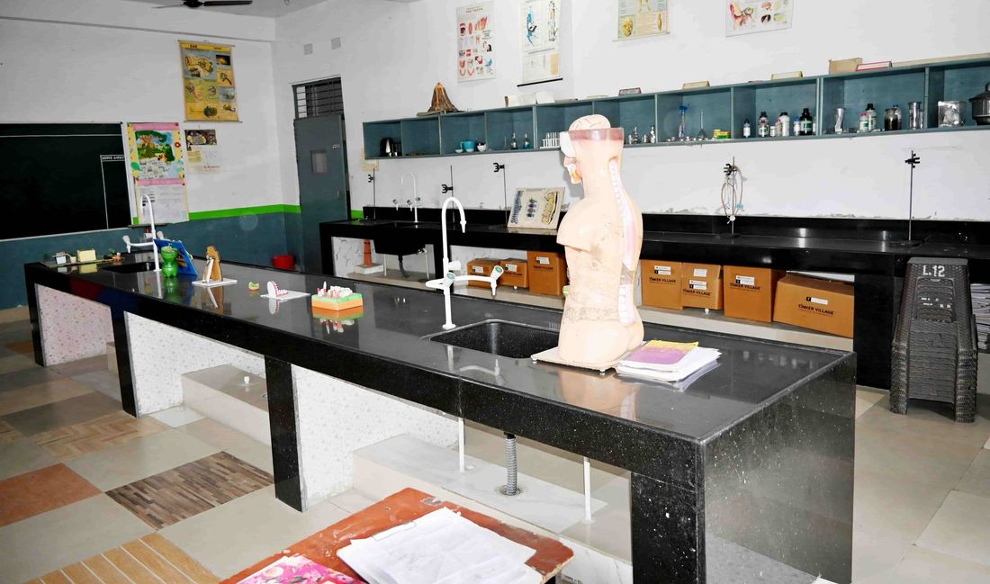 The composite laboratory at Sunbeam School Ballia between classes: a long bench with an anatomy model, sink and taps, reagent shelves along the back wall