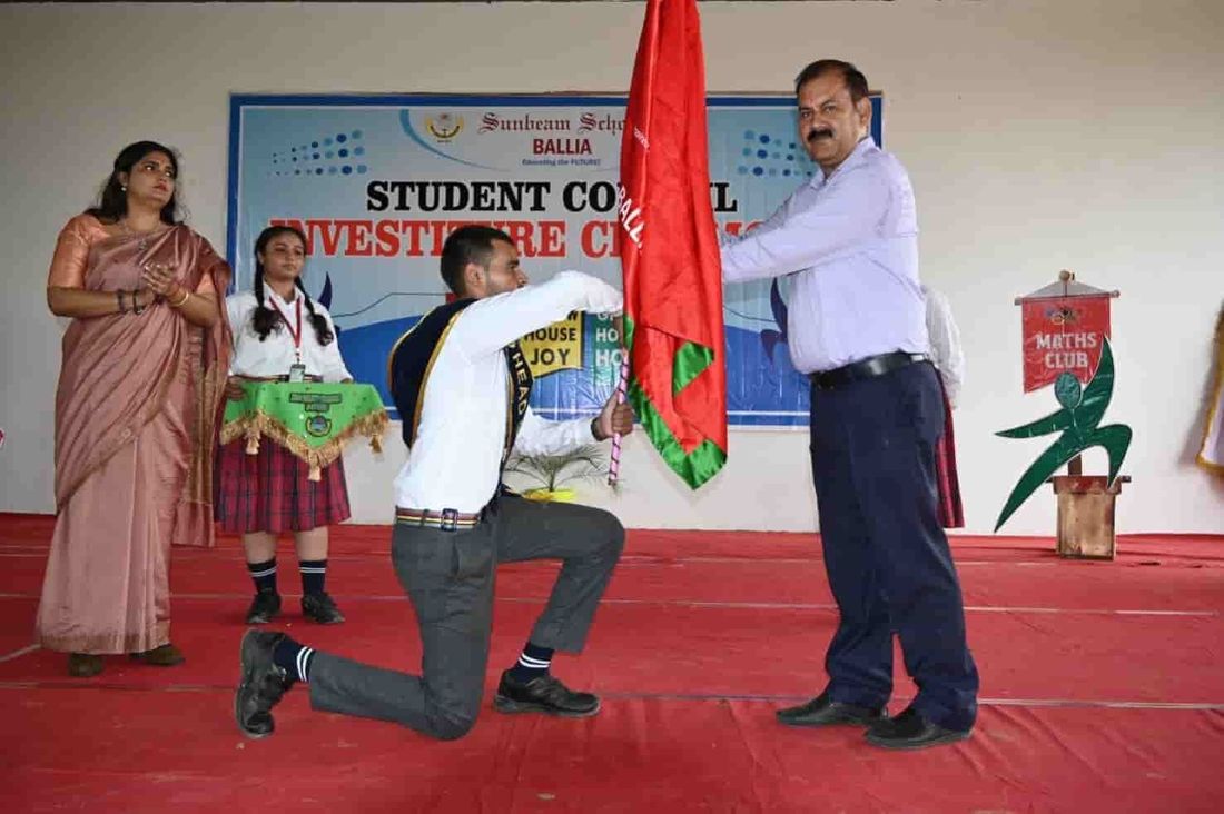 A house captain at Sunbeam School Ballia kneeling to receive the house flag