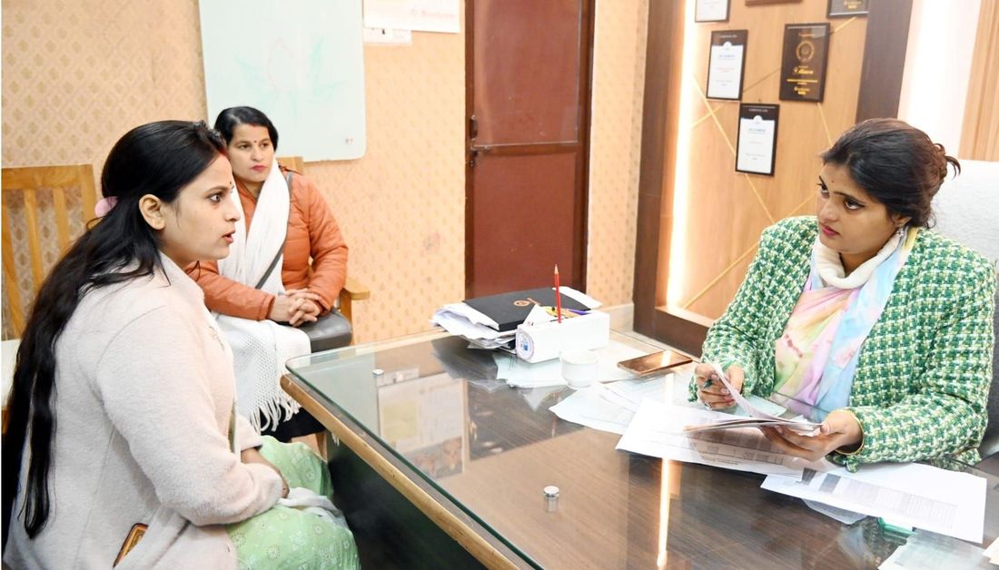 Two parents in conversation with a member of staff across a desk at Sunbeam School Ballia