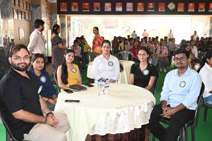 Six alumni of Sunbeam School Ballia seated at a round table in their Pradiptam badges, students of the school in rows behind them.