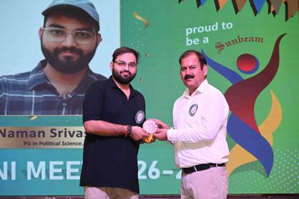 An alumnus of Sunbeam School Ballia taking his commemorative medallion from a member of staff, his photograph and postgraduate subject on the screen behind.