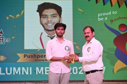 An alumnus of Sunbeam School Ballia receiving his medallion, the screen behind naming his batch and the medical degree he is reading for.