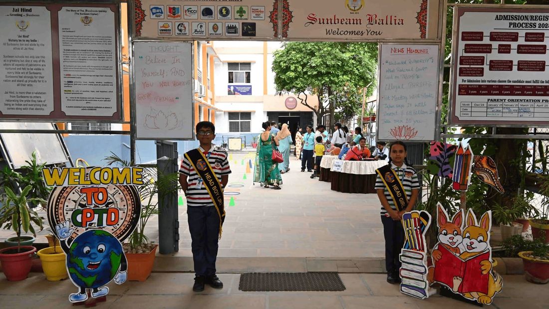 The entrance to Sunbeam School Ballia on Parent-Teacher Day, the Head Boy and Head Girl standing at the welcome board with parents arriving at the help desks beyond