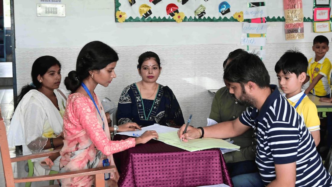 A teacher at Sunbeam School Ballia going through a report with parents at a classroom desk on Parent-Teacher Day