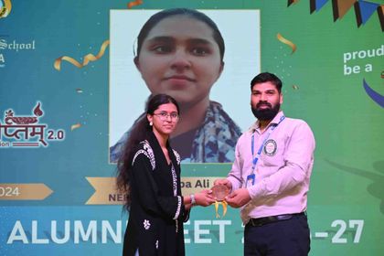 An alumna of the 2024 batch receiving her medallion, the screen behind carrying her photograph and the examination she cleared.