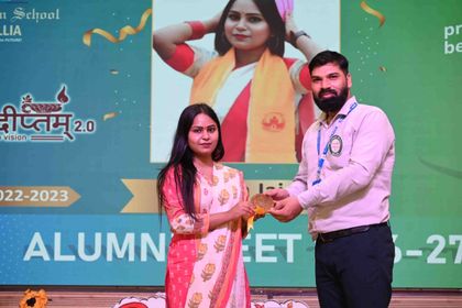 An alumna of the 2022–23 batch receiving her medallion at Pradiptam 2.0, a photograph of her dancing on the screen behind.
