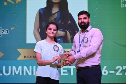 An alumna of Sunbeam School Ballia receiving her medallion, her science degree named on the screen behind her.