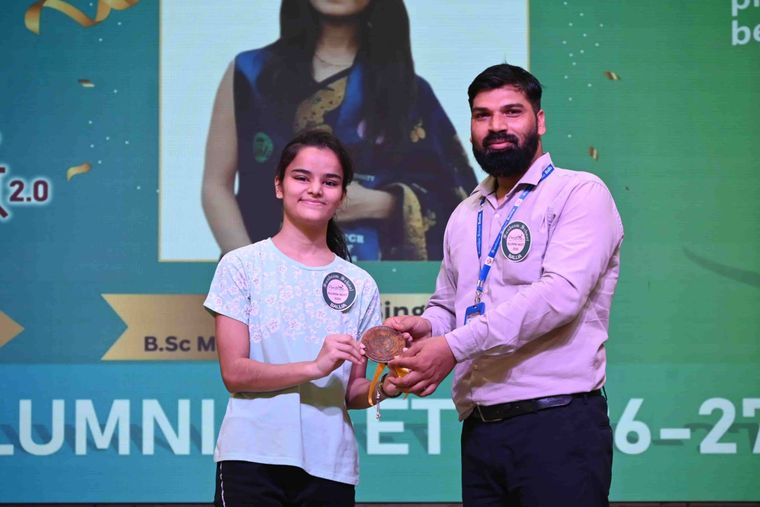 An alumna of Sunbeam School Ballia receiving her medallion, her science degree named on the screen behind her.