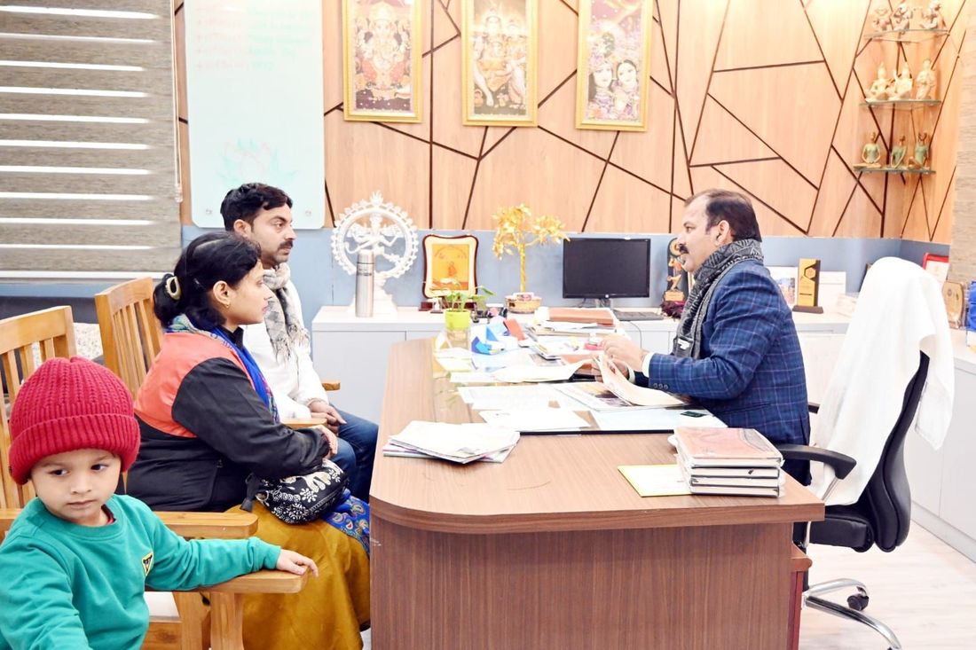 A mother, father and small child seated across a desk from a member of staff at Sunbeam School Ballia during a Parent's Orientation Programme