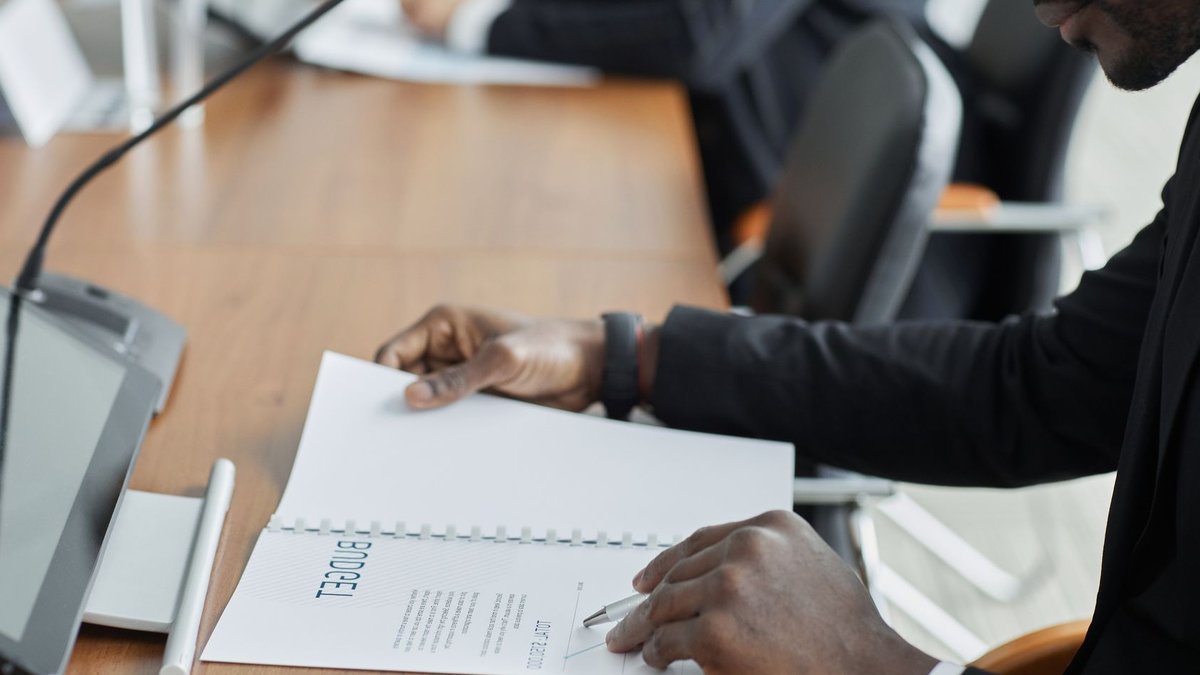 UAE Approves Large Federal Budget Increase Professional businessman examining budget documents during an office meeting, showcasing focus and analysis.