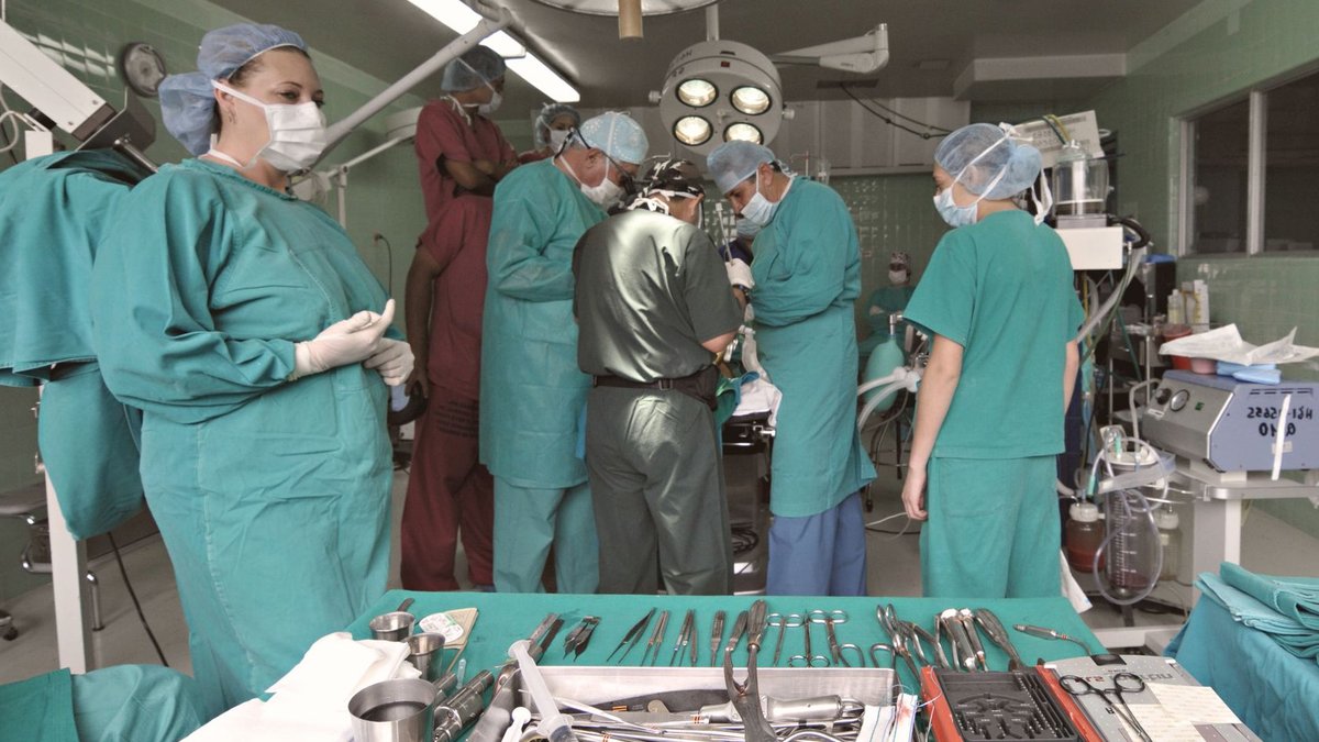 Medical team conducting surgery in a sterile operating room with surgical tools on display.