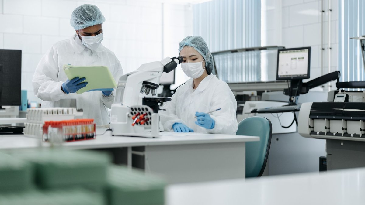 TY1 Drug Reduces Scarring in Scleroderma Lab Study Researchers wearing protective gear analyze samples in high-tech laboratory setting.