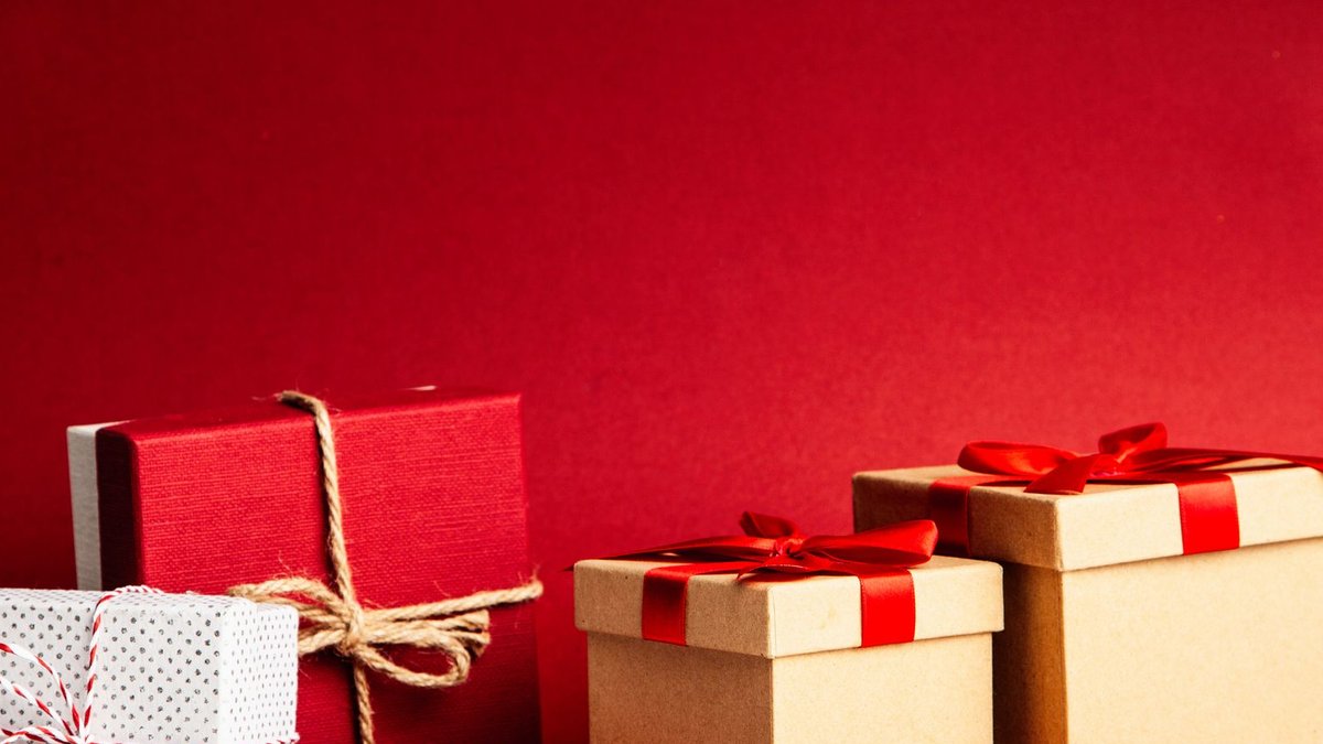 A collection of colorful gift boxes with ribbons on a rich red background, perfect for holiday themes.