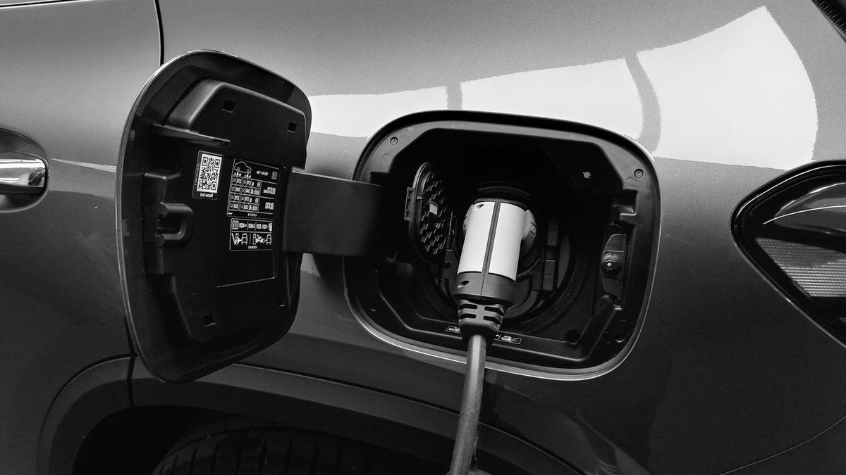 Toyota Europe launches shared hybrid platform, 15% gains Close-up black and white image of an electric vehicle charging at a station.