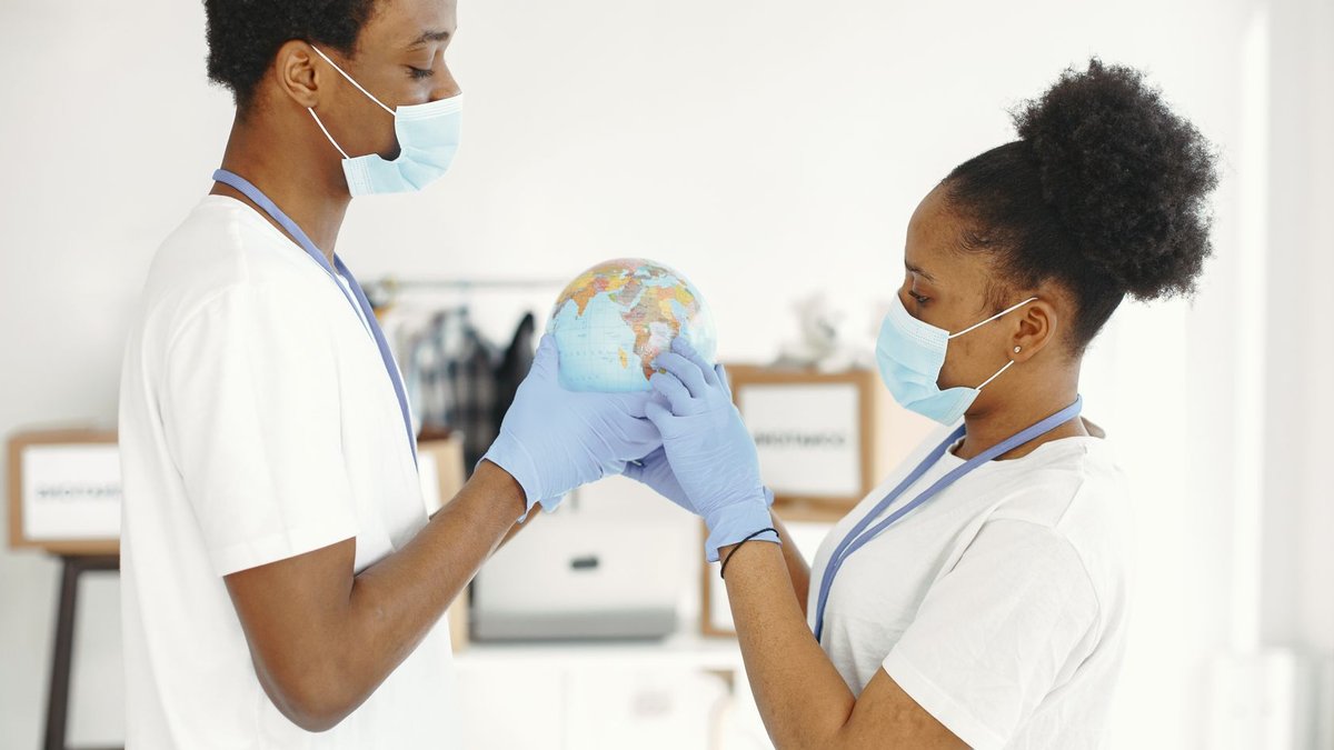 Medical professionals in masks and gloves hold a globe, symbolizing global health care efforts.