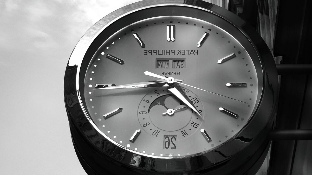 Patek Philippe Opens Bangkok Boutique A close-up of a Patek Philippe wall clock with reflective surface showing time.