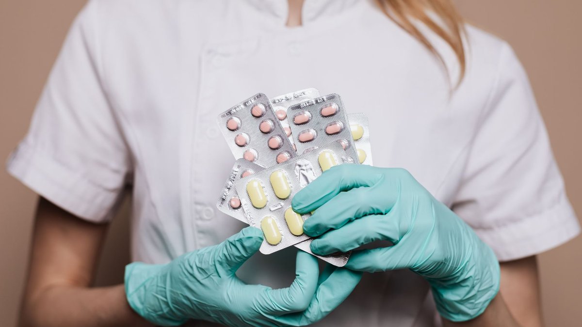 India Seeks to Expand Pharmacists Role in Healthcare Close-up of a healthcare professional wearing gloves and holding blister packs of medication.