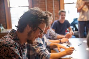 men smile as they sit doing UX