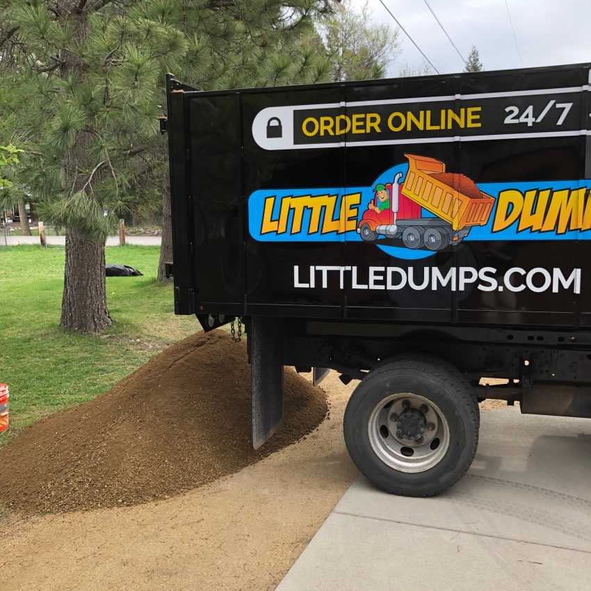 An image of the rear half of a smaller dump truck and a pile of decomposed granite product that was delivered.