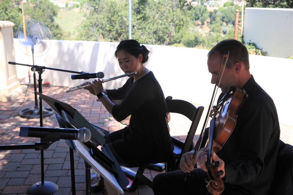 Weili playing the flute next to another musician, who is playing the violin