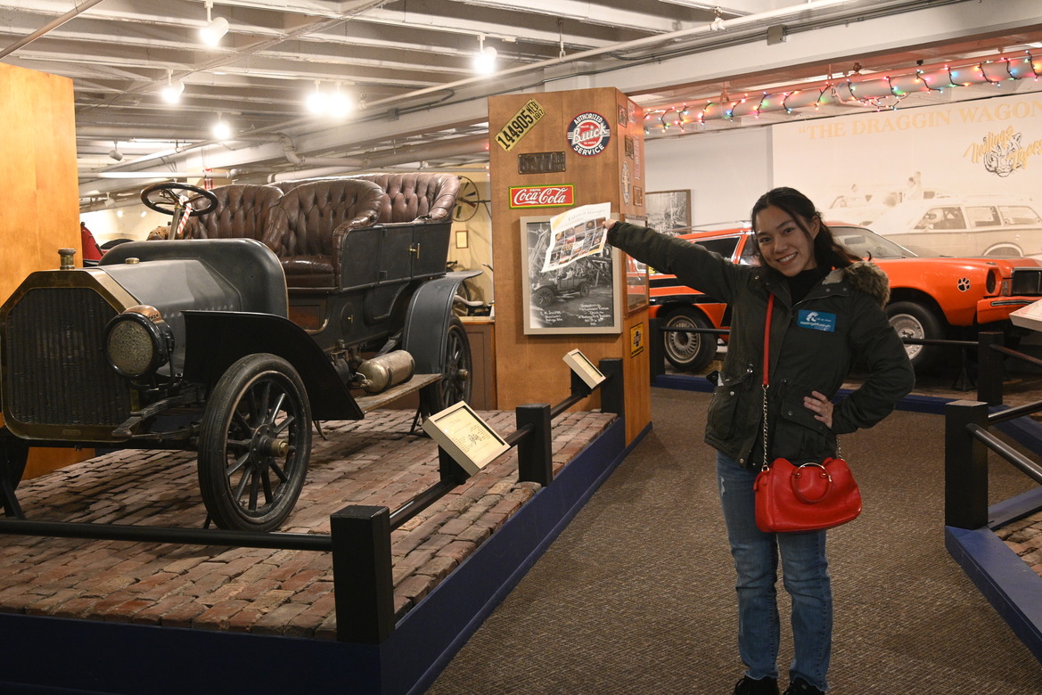 Thu posing in front of old cars