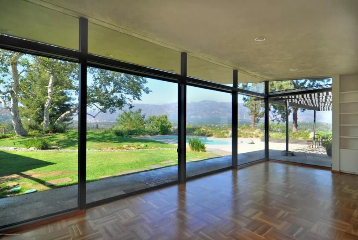 One room has ceiling to floor windows that bring in some light and offers a scenic view of the backyard and the hills