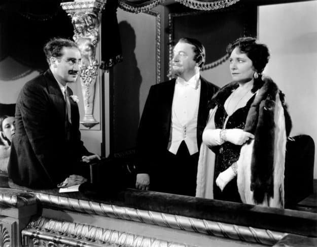 Groucho Marx talking to Sig Ruman and Margaret Dumont in a opera box