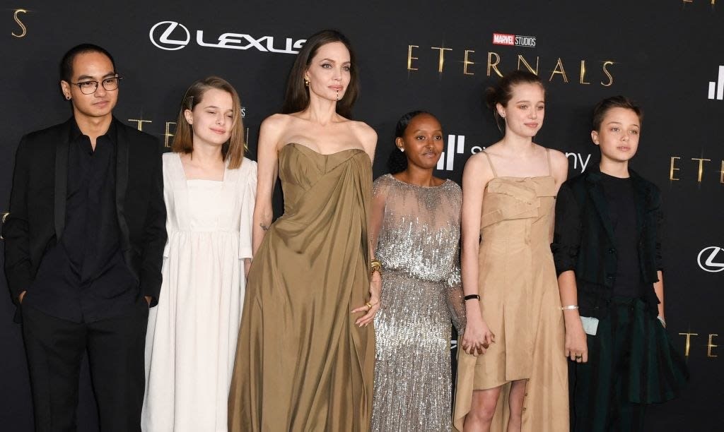 Maddox wears a dark suit, Vivienne wears a long sleeve dress, Zahara wears a sparkly gown, Shiloh wears a thin strap gown, Knox wears a dark suit, and Angelina Jolie wears a strapless gown,