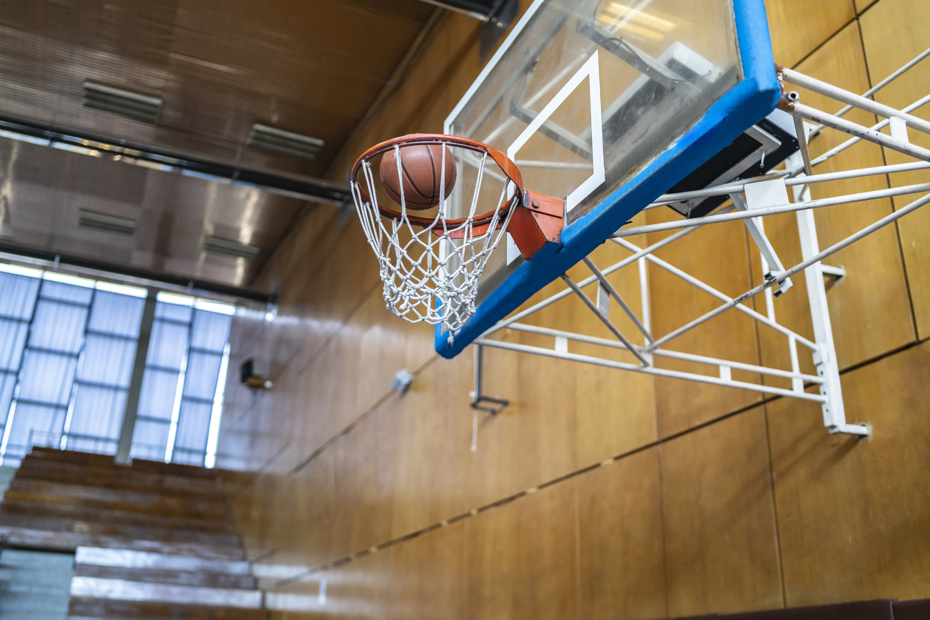 a basketball going through a hoop in the school gym