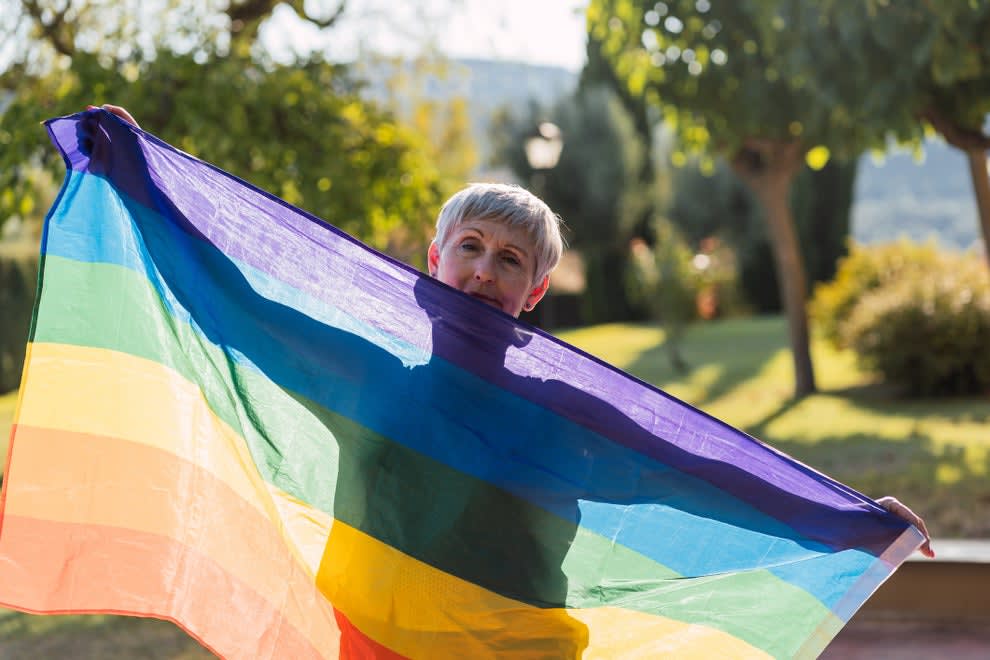 An older woman draping herself with a Pride flag