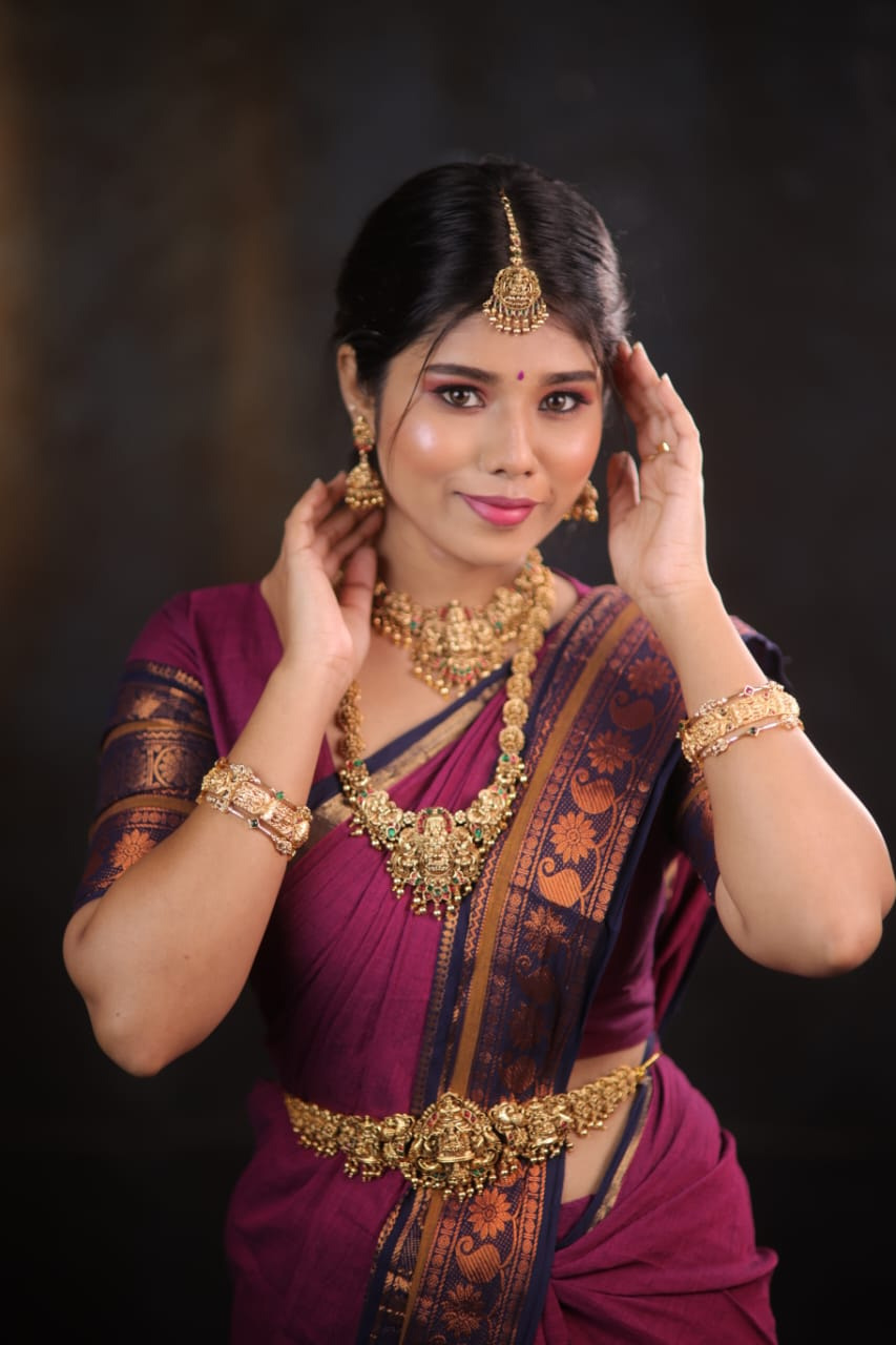Bride in a magenta silk saree with a navy peacock border and layered Lakshmi temple jewellery, styled in Kundrathur, Chennai